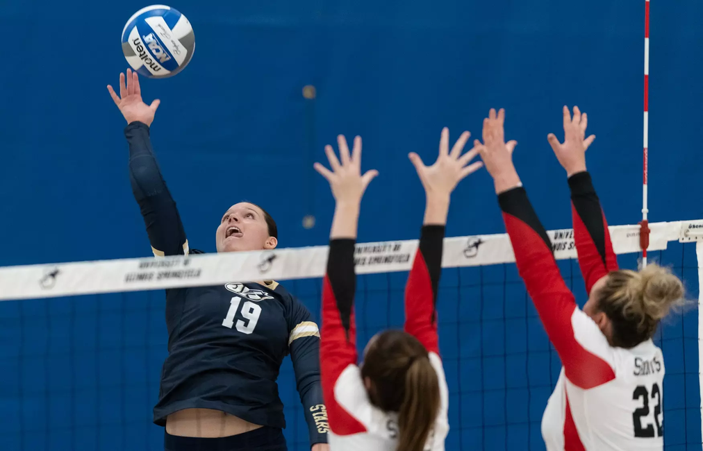 Makenna Cox seen through the net as Saints go up for a block