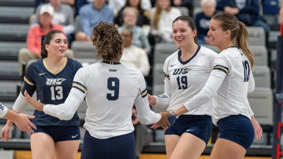 UIS volleyball players engaging on court between points