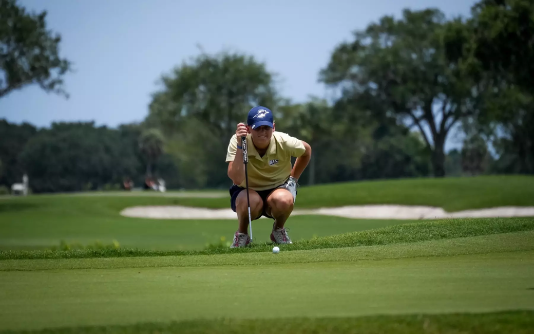 Elaine Grant in gold UIS polo and blue UIS hat golfing
