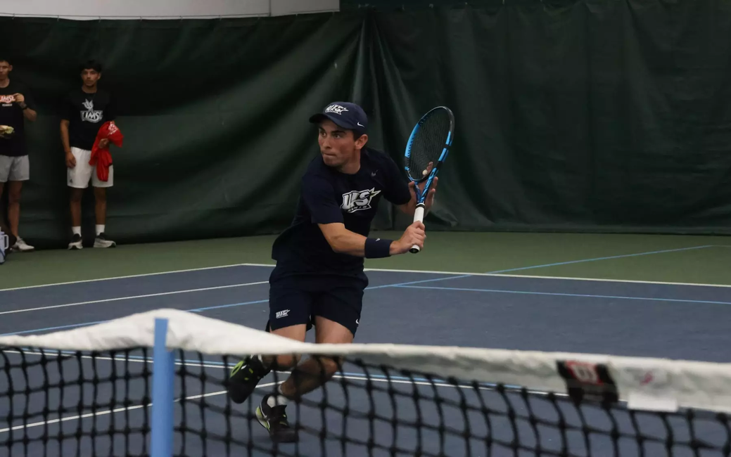 Pablo Herrera playing tennis in UIS blue in indoor facility