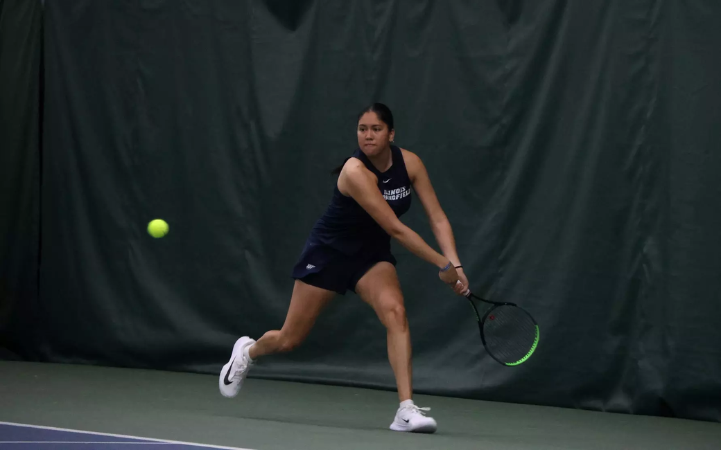 Cristina Mendoza Romero playing tennis in blue UIS uniform