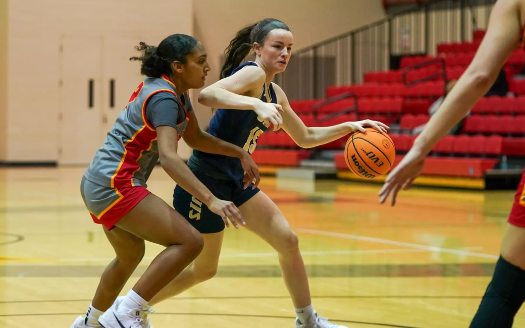 Molly Knight playing basketball in blue UIS uniform