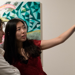 Two women discussing a painting at the UIS Visual Arts Gallery