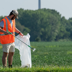 a volunteer picking up trash in a field