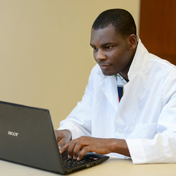 student in lab coat at computer
