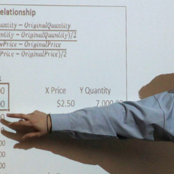 accounting professor pointing to formulas on the whiteboard