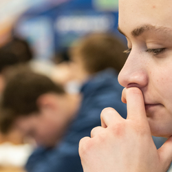 a student at their desk in a classroom looking down at a laptop