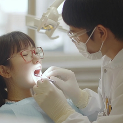 a dentist working on the mouth of a young patient