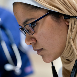 a nursing student looking at a patient with a stethoscope on
