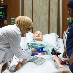 nursing students in the simulation lab looking over a dummy