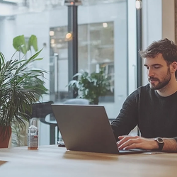 a man sitting at a table looking at his laptop