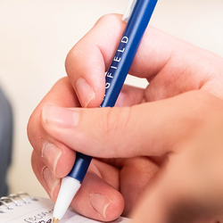 closeup image of a hand writing with a blue UIS pen