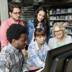 5 members's looking at a computer or a desktop in the library space 
