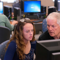a professor explaining something on a computer to a student