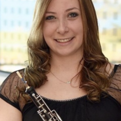 Suzanne Segredo smiling and holding a musical instrument indoors.