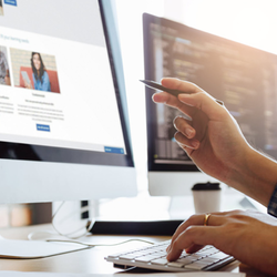 Two people at computers discussing code and website content.