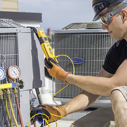 Technician checking HVAC unit on rooftop with tools and gauges.
