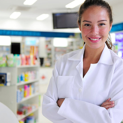 Pharmacist smiling in a brightly lit pharmacy.