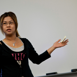 a female teacher speaking to the class in front of a white board