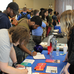 Busy career fair with people interacting at tables.