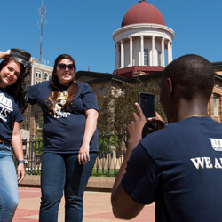 Three people outside posing for a photo in front of a historic building.