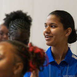 People clapping in a dimly lit room, wearing casual blue shirts.