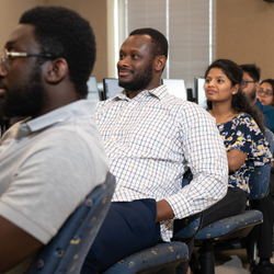 People seated in a classroom, attentively looking forward.
