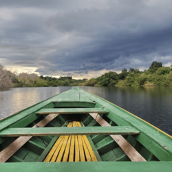 View out of the front of a green boat onto the Amazon river under dramatic skies
