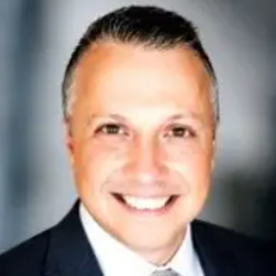 Smiling man in a suit against a dark background