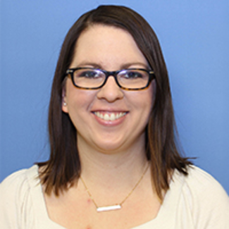 Smiling woman with glasses against a blue background.