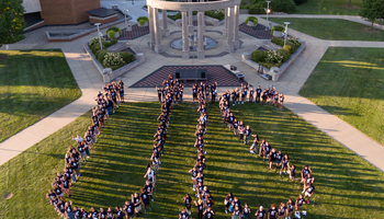 Students form the letters "UIS" in front of the Colonnade.