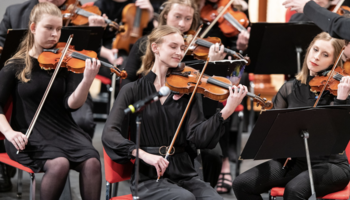Photo of violin players in an orchestra