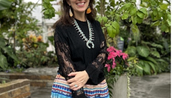 Picture of a woman standing with a colorful skirt in front of a tree