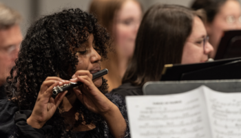 Musicians playing instruments in an orchestra setting.