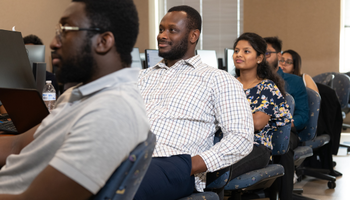 People seated in a classroom, attentively looking forward.