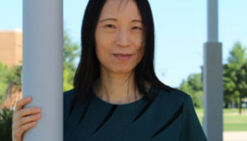 Woman stands outdoors, smiling under a clear blue sky
