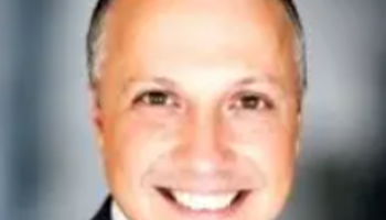 Smiling man in a suit against a dark background