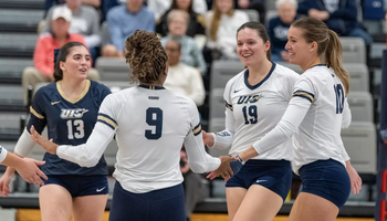 UIS volleyball players engaging on court between points