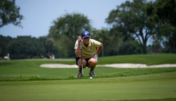Elaine Grant in gold UIS polo and blue UIS hat golfing