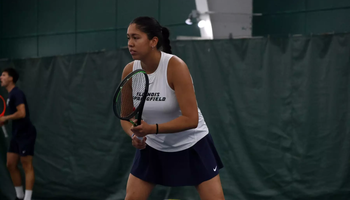 Cristina Mendoza Romero playing tennis in blue and white UIS uniform