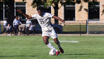 Promis Ahupa playing soccer in white UIS uniform