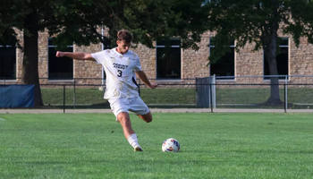 Adam Knaze playing soccer at UIS in white uniform
