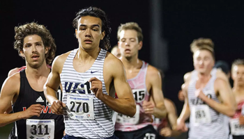 Matt Padilla running outdoor track in white UIS jersey