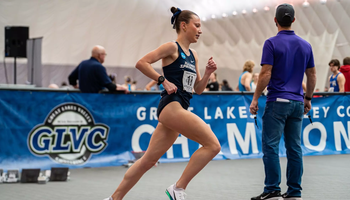 Madelyn Miller-Ross running indoor track in blue UIS uniform