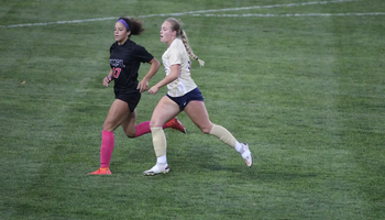 Carolyne Mathenia running on the pitch with an opponent