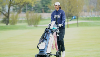 Ira Joshi pushing bag cart on golf course