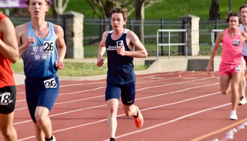 Garrett Wagoner running outdoor track in blue UIS uniform