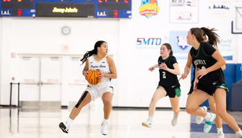 Kayla Rice playing basketball in white UIS uniform