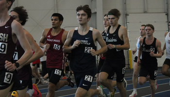 Owen Whelan running indoor track in blue UIS uniform