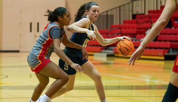 Molly Knight playing basketball in blue UIS uniform